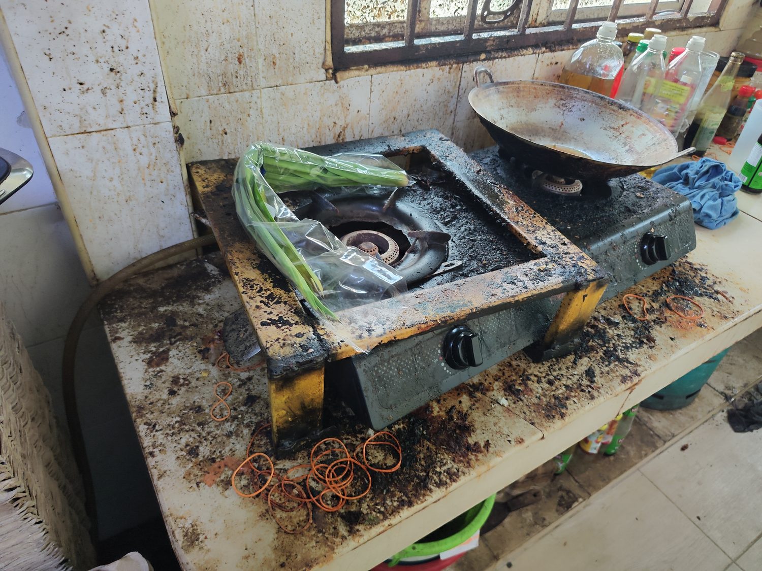Grease buildup on the stove and surrounding kitchen tiles before cleaning