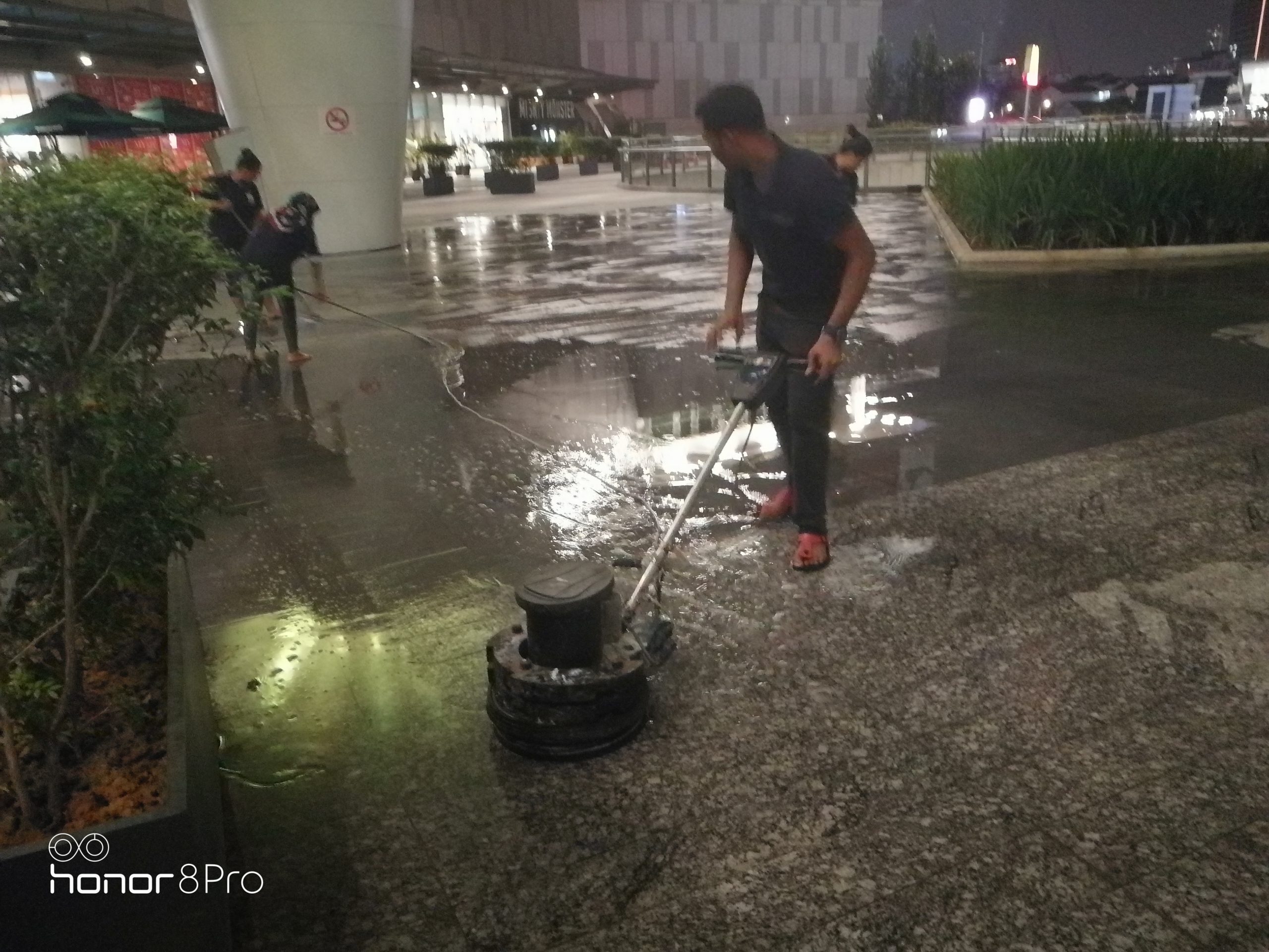 Natasya team using a floor machine to clean an outdoor common area